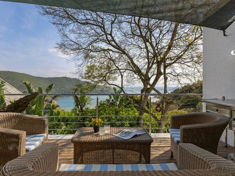 A covered balcony featuring timber decking and a stainless steel balustrade, offering scenic views of the surrounding landscape and water.