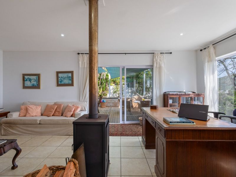 Spacious living room featuring a central freestanding fireplace, tiled flooring, and large sliding glass doors providing direct access to the outdoor patio area.