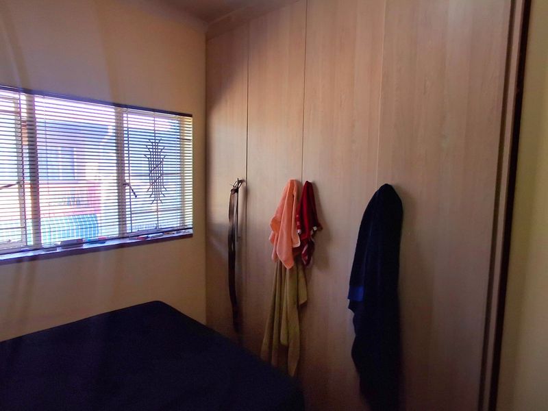 A bedroom featuring built-in cupboards and venetian blinds, providing functional storage and adjustable natural light control.