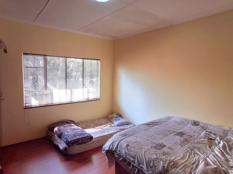 A bedroom featuring laminate flooring, a built-in wardrobe, and venetian blinds. The room requires minor ceiling repairs and cosmetic updates.