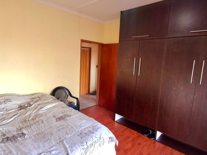 A bedroom featuring dark wood-finish built-in cupboards and laminate flooring, providing functional storage and a neutral living space.