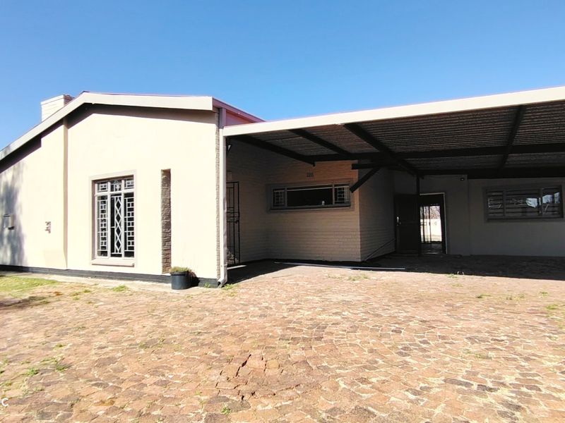Front exterior view of the house featuring a large covered carport and a paved driveway area.