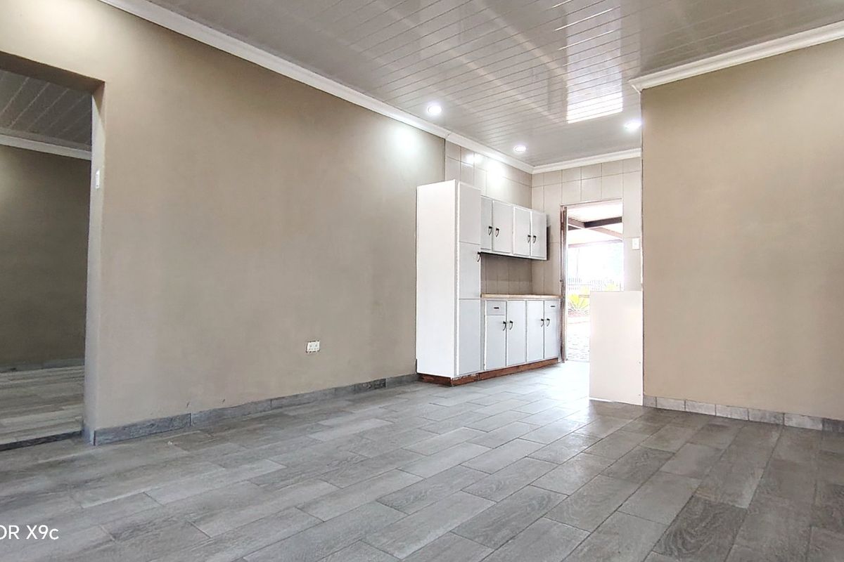 An empty kitchen area featuring tiled flooring, built-in white cabinetry, and recessed ceiling lighting, providing a clean and functional space ready for customization.