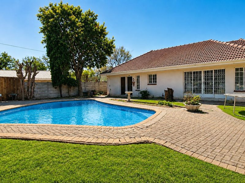 A well-maintained backyard featuring a swimming pool, paved patio area, and established lawn, providing a functional outdoor space for relaxation and entertainment.