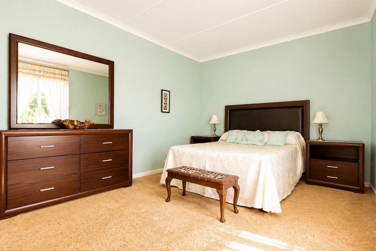 A well-maintained bedroom featuring neutral carpet flooring and coved ceiling cornices, providing a comfortable and functional living space.