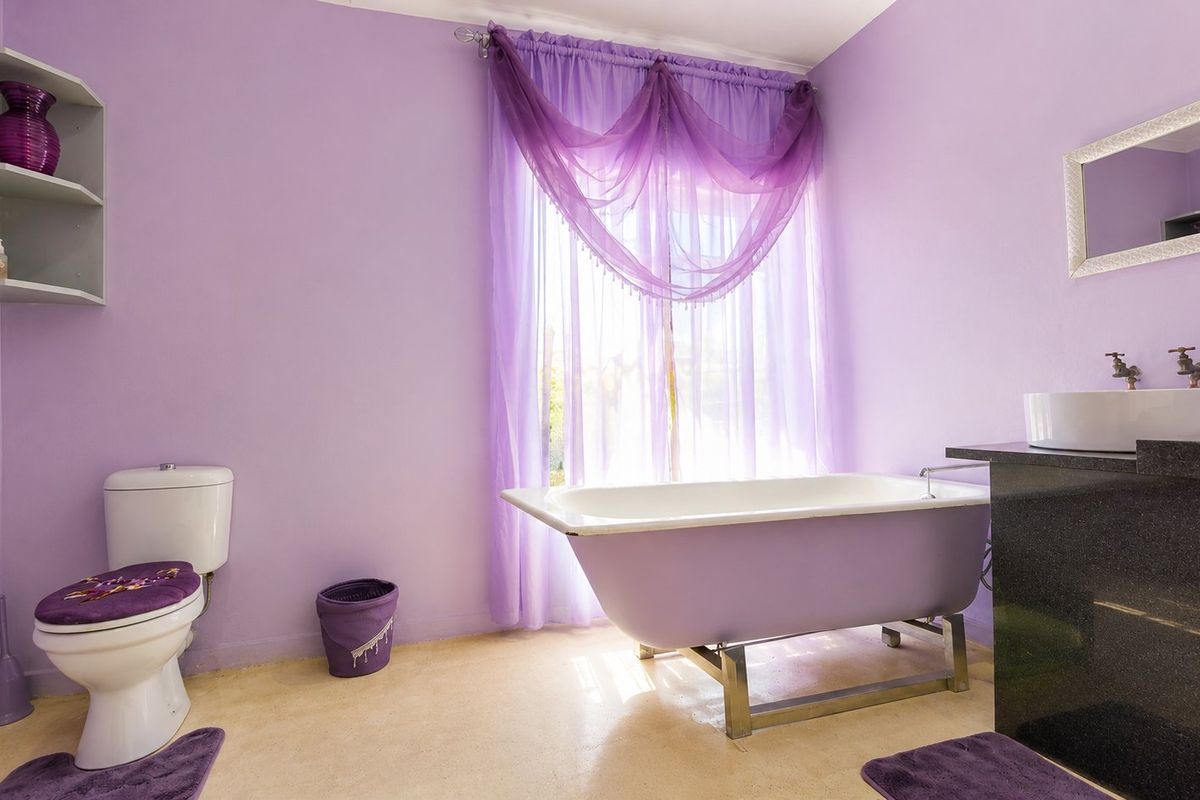 A bathroom featuring a freestanding bathtub, a vessel sink on a dark vanity countertop, and a wall-mounted shelving unit.