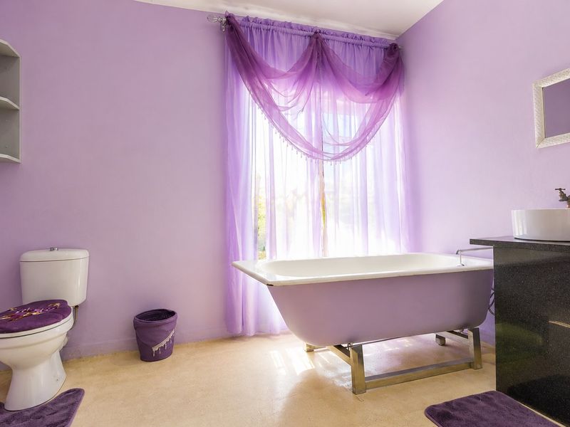A bathroom featuring a freestanding bathtub, a vessel sink on a dark vanity countertop, and a wall-mounted shelving unit.