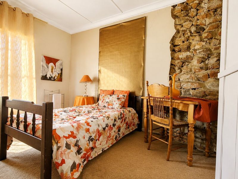 A bedroom featuring a rustic exposed stone wall, neutral carpeting, and coved ceiling details, offering a unique character-filled space.