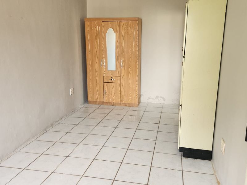 A simple bedroom featuring tiled flooring and plain walls, currently vacant and ready for renovation or personalization.