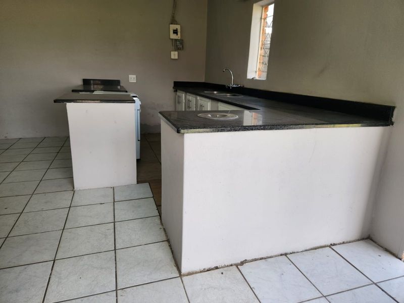 A functional kitchen space featuring granite countertops, built-in cabinetry, and tiled flooring, currently awaiting final finishes and personal touches.