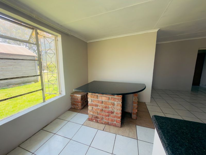 A kitchen area featuring a built-in brick breakfast bar with a granite countertop and ceramic tiled flooring.