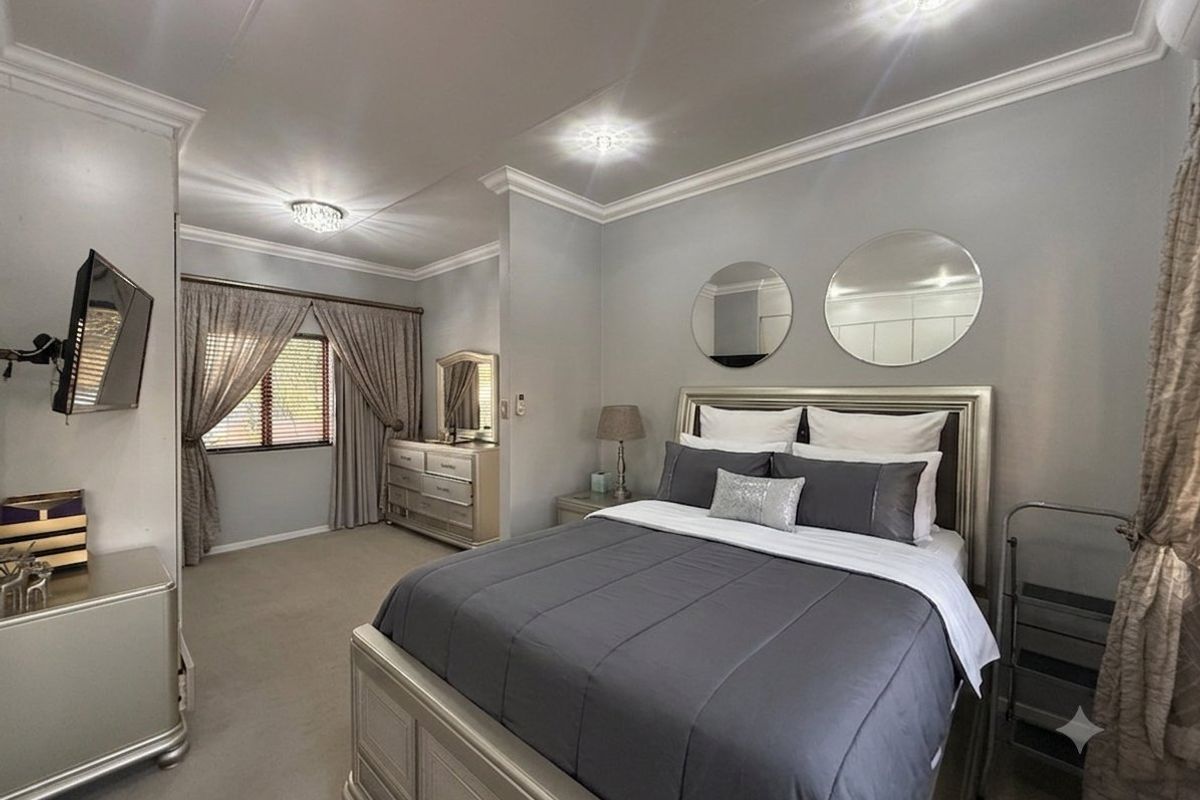 A well-maintained bedroom featuring crown molding, recessed lighting, and neutral carpeting, offering a comfortable and finished living space.