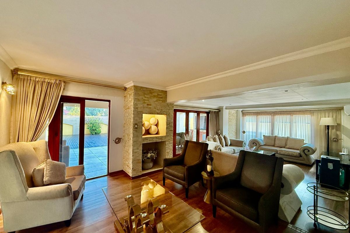 Spacious living room featuring laminate flooring, a central stone-clad fireplace with a recessed niche, and large sliding glass doors providing access to the patio.