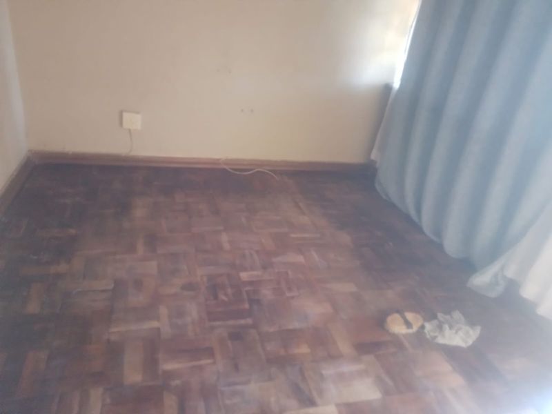 An empty bedroom featuring original parquet flooring and neutral wall finishes, offering a blank canvas for renovation or interior design updates.