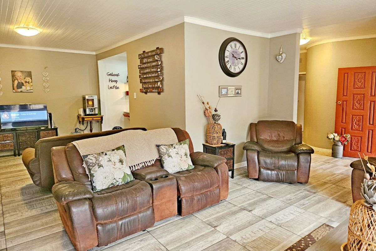 A spacious living area featuring light-toned tiled flooring, a beadboard ceiling with coving, and a distinctive solid wood entrance door.