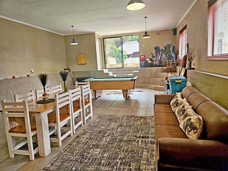 Spacious open-plan living and dining area featuring tiled flooring, pendant lighting, and a raised platform area with access to the outdoors.