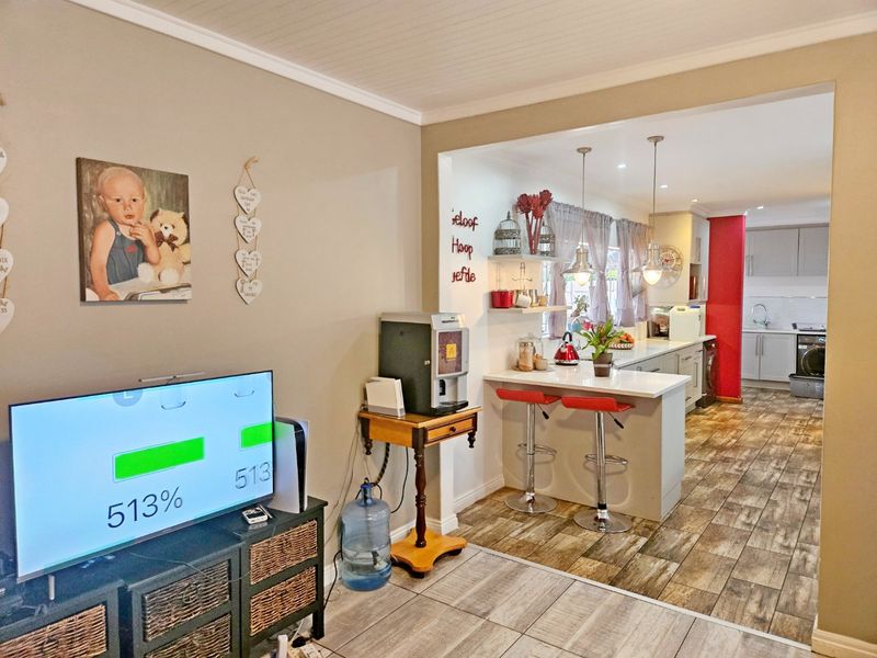 Open-plan living area featuring a modern kitchen with a central island, stone countertops, and tiled flooring, seamlessly connected to the adjacent living space.