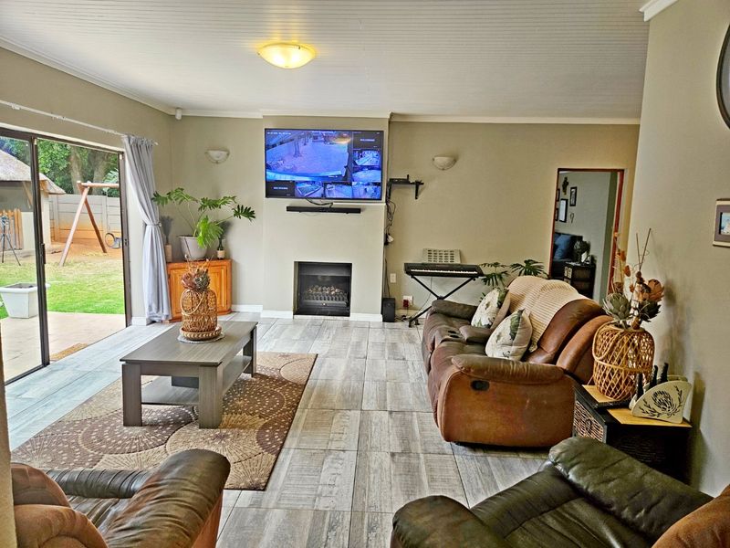 Spacious living room featuring tiled flooring, a built-in fireplace, and large sliding glass doors providing direct access to the rear garden area.