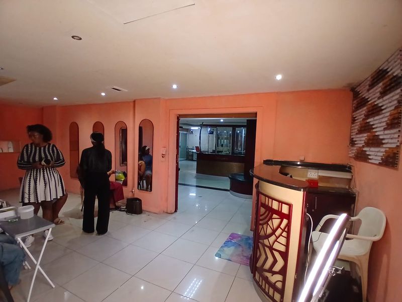 Commercial entry area featuring a reception desk, tiled flooring, and recessed lighting, leading into an adjacent office or service space.
