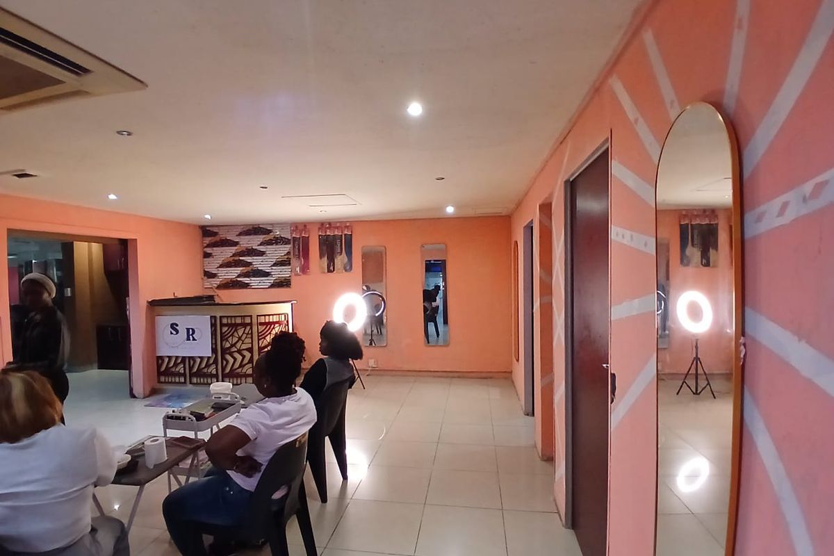 Open plan commercial space featuring tiled flooring, recessed lighting, and a built-in reception desk, suitable for a salon or retail environment.