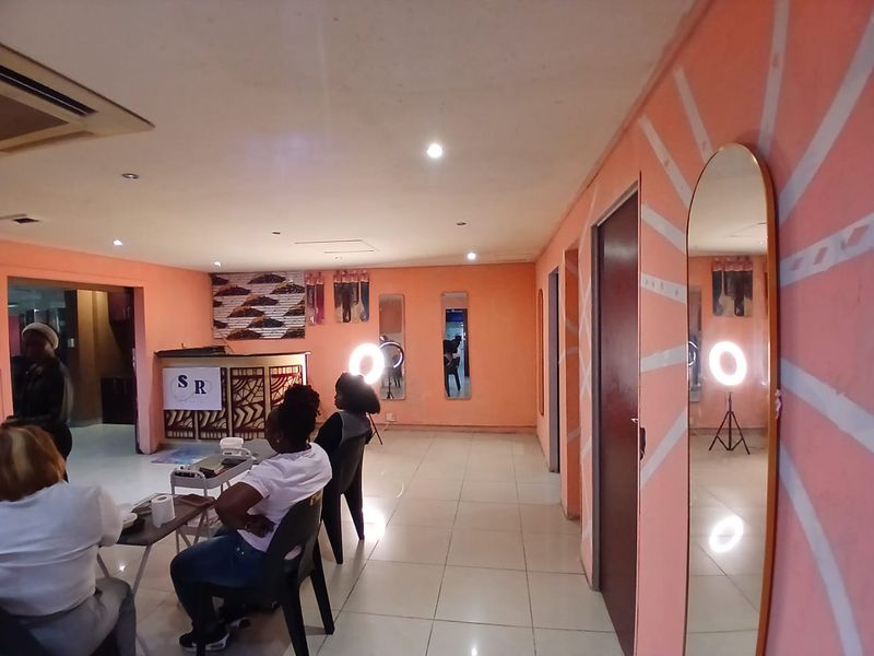 Open plan commercial space featuring tiled flooring, recessed lighting, and a built-in reception desk, suitable for a salon or retail environment.