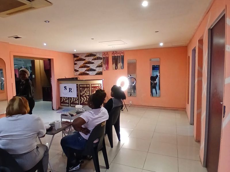 A commercial space featuring tiled flooring, recessed lighting, and a built-in reception desk, currently utilized as a salon or training area.