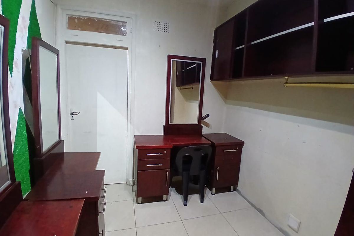 A bedroom featuring built-in dark wood cabinetry and vanity units with tiled flooring, requiring cosmetic updates to improve the overall aesthetic.