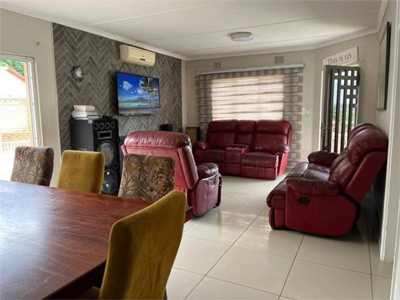 Spacious open-plan living and dining area featuring a decorative herringbone tile feature wall, tiled flooring, and split-system air conditioning.