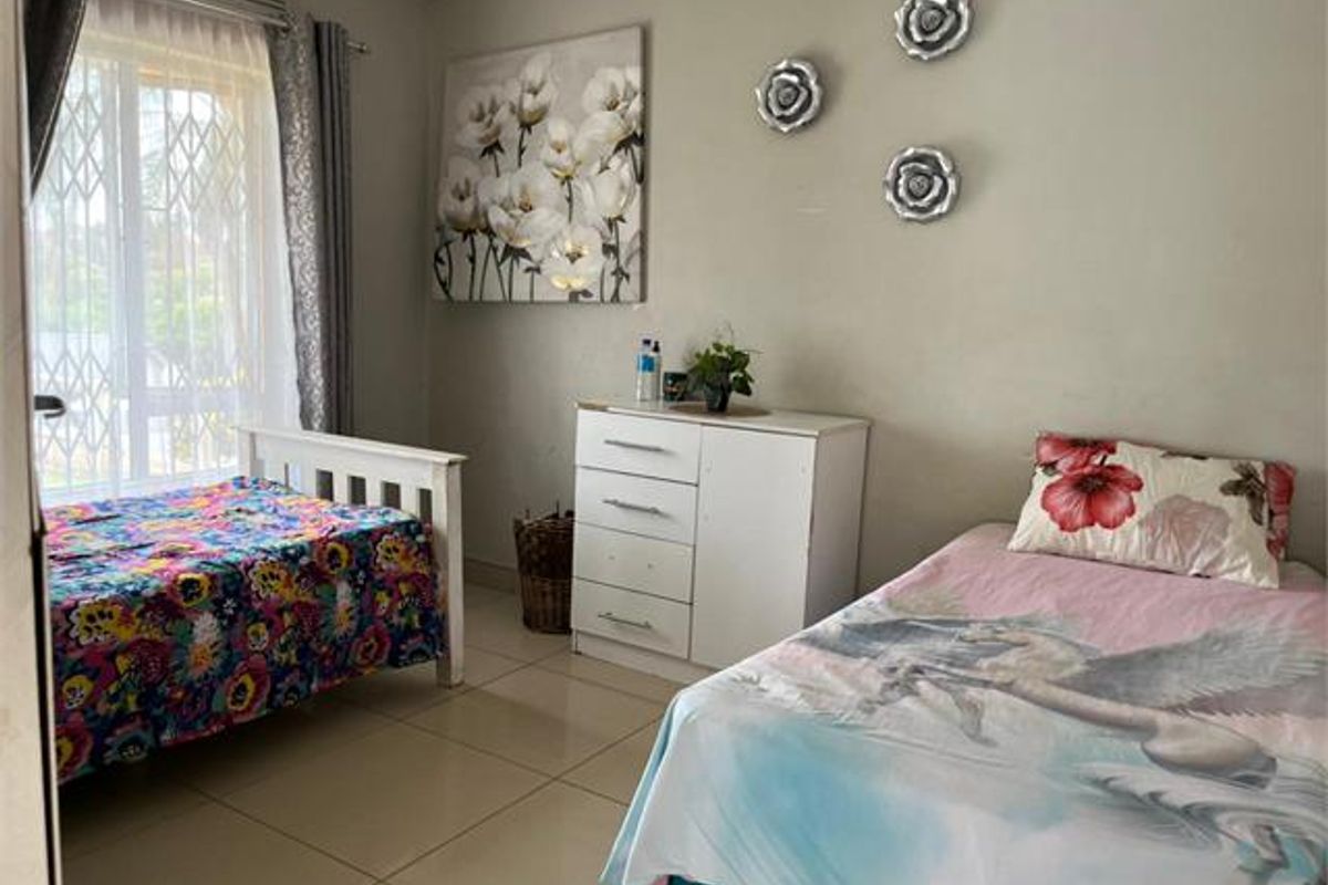 A functional bedroom featuring tiled flooring and a sliding door with an integrated security gate, providing access to the exterior.