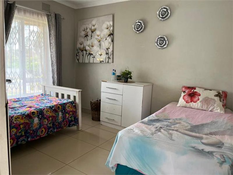 A functional bedroom featuring tiled flooring and a sliding door with an integrated security gate, providing access to the exterior.