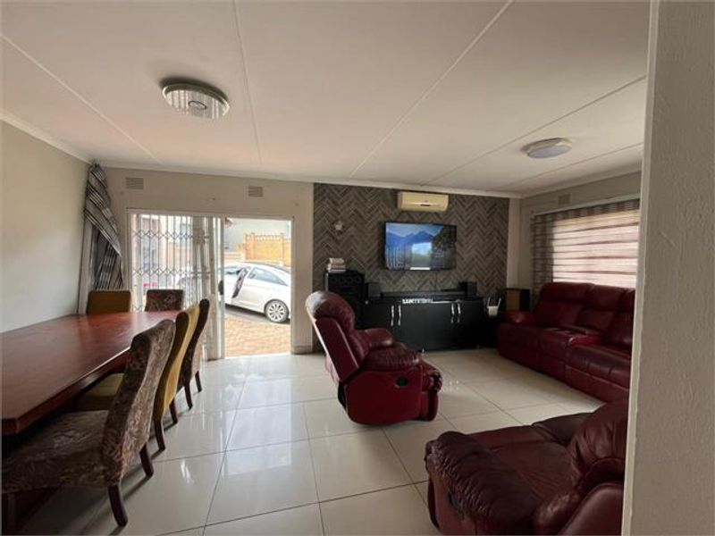 Spacious open-plan living and dining area featuring large format floor tiles, a feature wall, and direct access to the exterior via a sliding door.