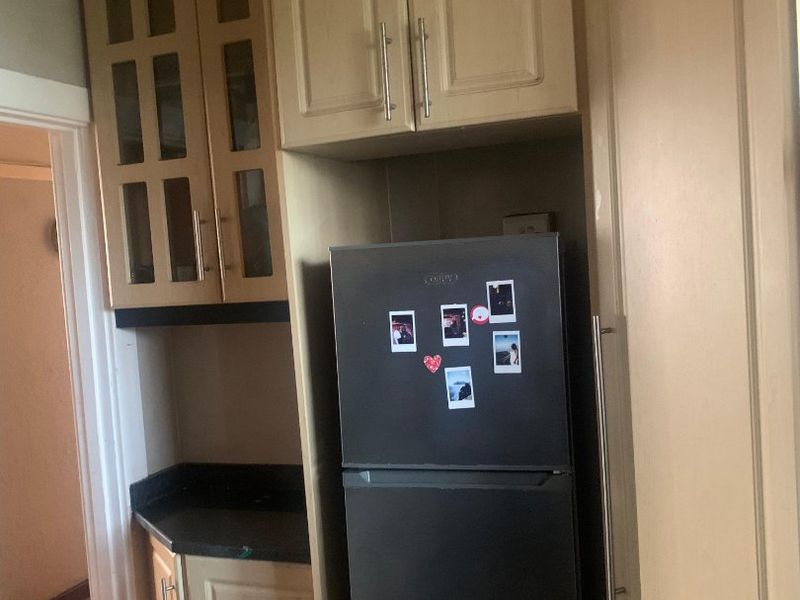 A compact kitchen area featuring built-in wooden cabinetry and dark laminate countertops, providing functional storage and preparation space.