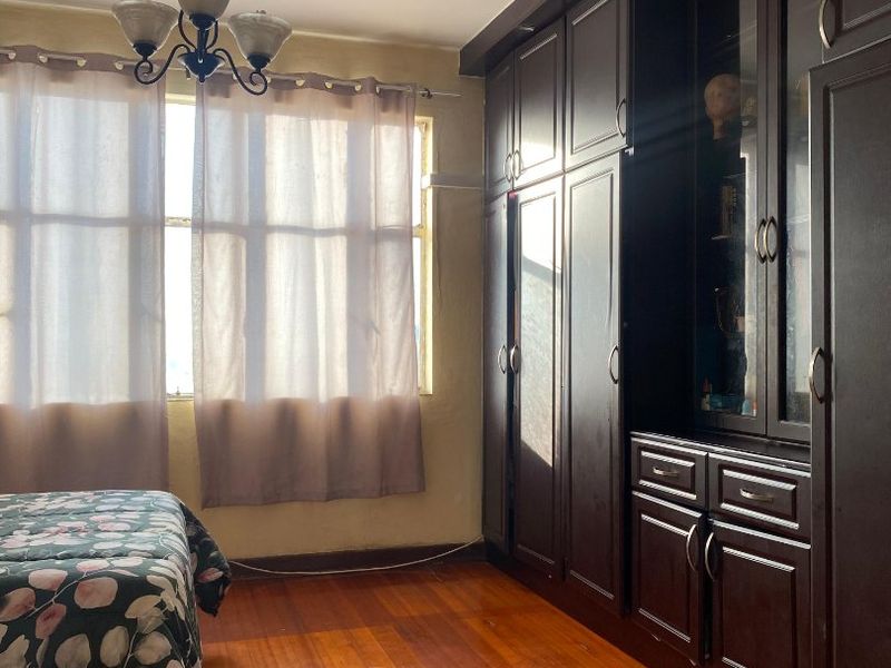 Bedroom featuring dark wood built-in cabinetry, hardwood flooring, and a classic ceiling light fixture.