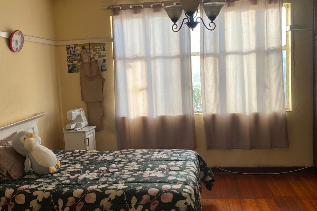 A bedroom featuring original hardwood flooring, a classic ceiling chandelier, and a picture rail, requiring cosmetic updates to the wall finishes.