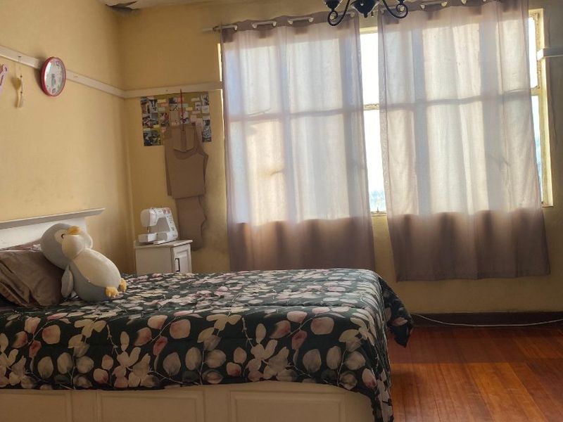 A bedroom featuring original hardwood flooring, a classic chandelier, and a picture rail, requiring cosmetic updates to the walls and ceiling.