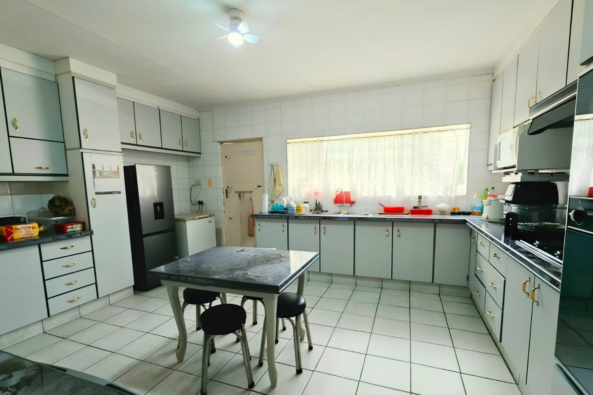 A functional kitchen featuring tiled flooring, extensive built-in cabinetry, a tiled backsplash, and integrated appliances including an oven and extractor fan.