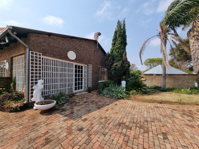 Rear view of the property featuring a brick facade, paved patio area, and secure access points leading into the home.