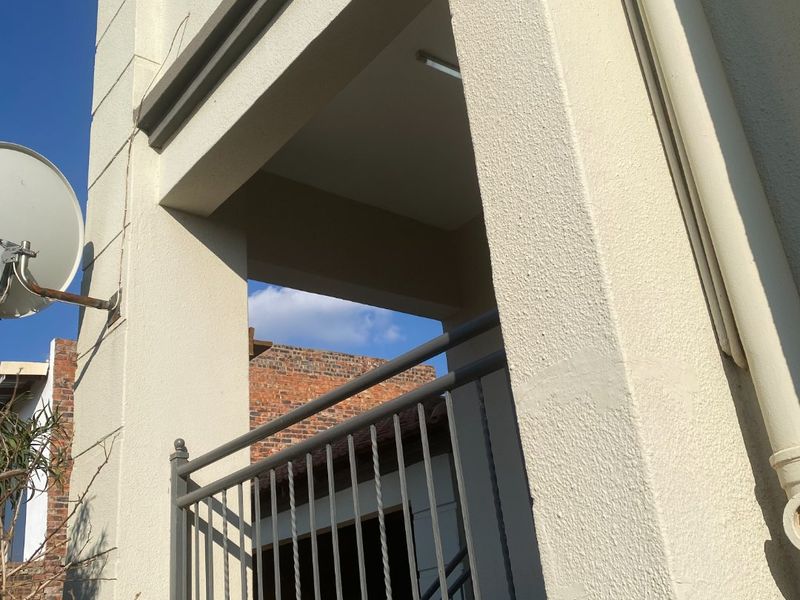A view of an elevated balcony featuring a metal balustrade and exterior plaster finish, showing standard residential construction.
