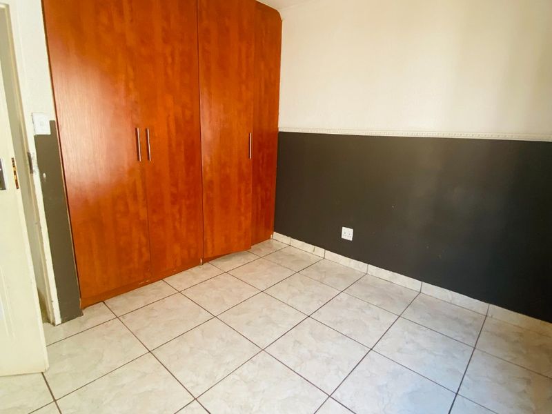 A vacant bedroom featuring tiled flooring, a built-in wooden wardrobe, and two-tone wall paint with decorative chair rail molding.