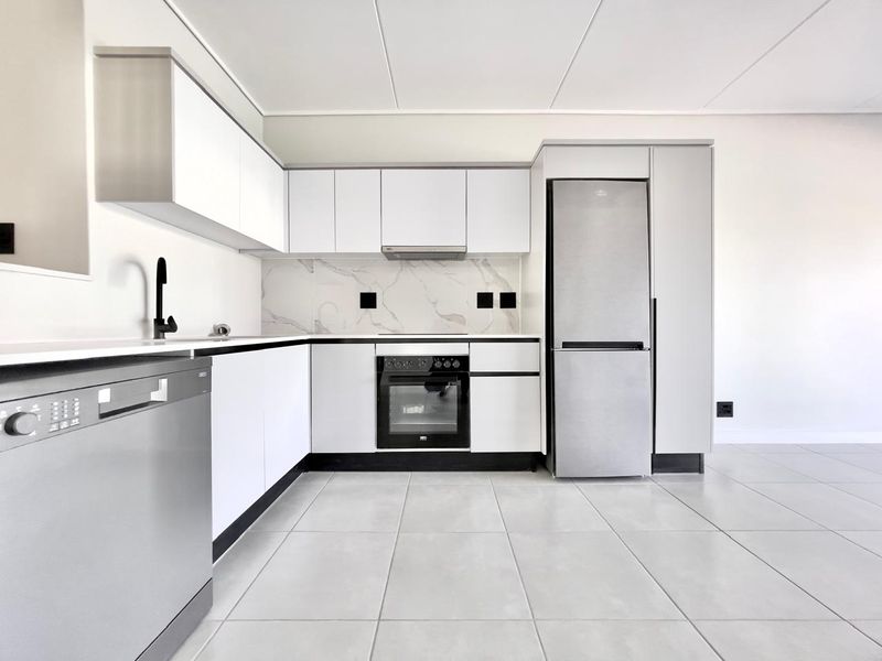 Modern kitchen featuring white cabinetry, marble-look splashback, integrated oven, extractor fan, and sleek tiled flooring in a clean, minimalist design.