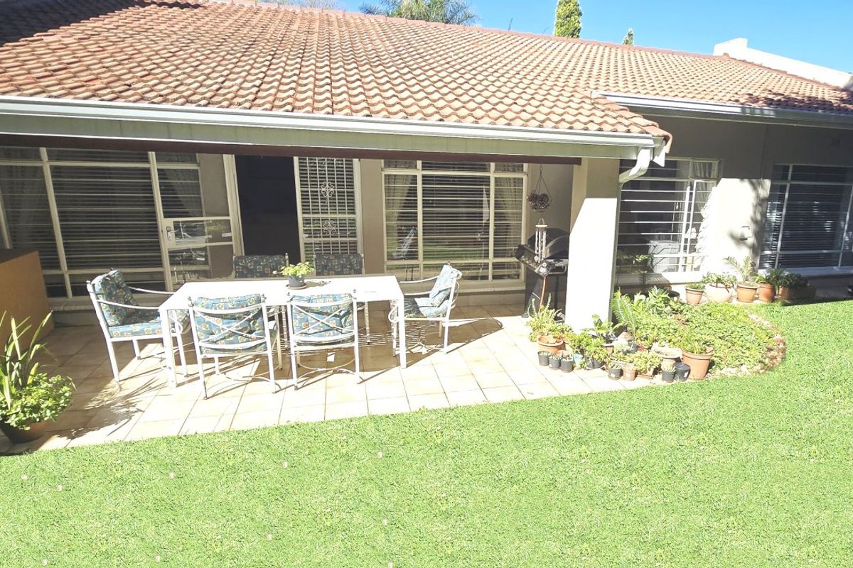 A covered outdoor patio area featuring tiled flooring, direct access to the interior through sliding glass doors, and views over the garden.