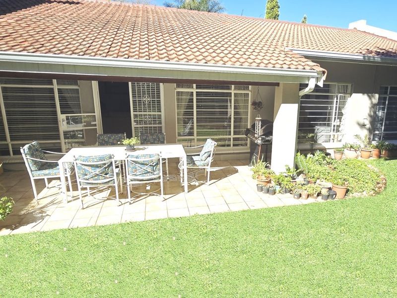 A covered outdoor patio area featuring tiled flooring, direct access to the interior through sliding glass doors, and views over the garden.