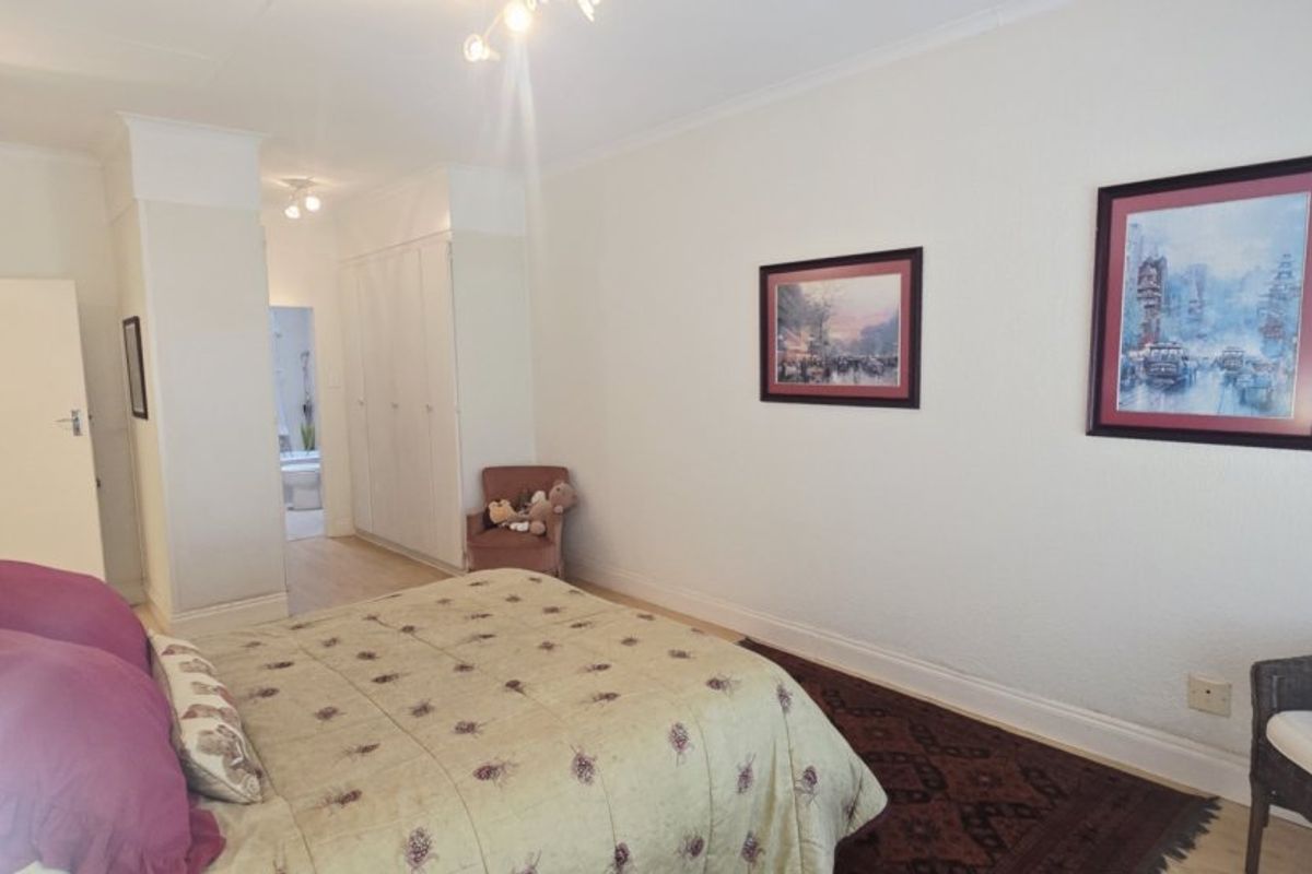 A well-proportioned bedroom featuring built-in cupboards, coved cornicing, and neutral wall finishes, offering a functional and comfortable living space.