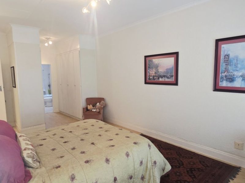 A well-proportioned bedroom featuring built-in cupboards, coved cornicing, and neutral wall finishes, offering a functional and comfortable living space.