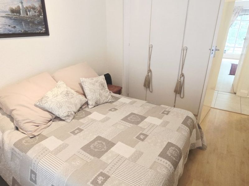 A bedroom featuring laminate flooring and a built-in wardrobe with white doors, providing functional storage space.