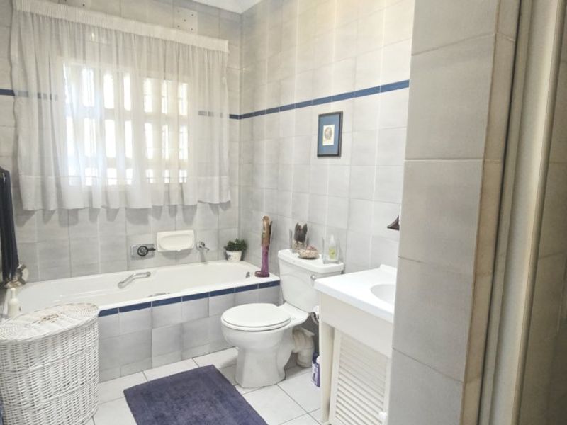 A functional bathroom featuring a bathtub, toilet, vanity, and a separate shower enclosure with neutral wall and floor tiling.