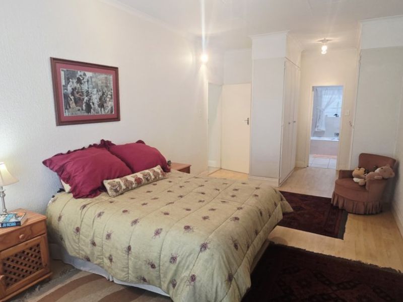 A well-proportioned bedroom featuring built-in cupboards, laminate flooring, and direct access to an en-suite bathroom.