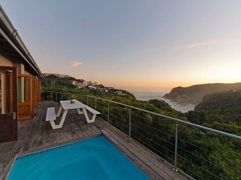 An elevated timber deck featuring a plunge pool and stainless steel balustrade, offering expansive coastal and cliffside views.
