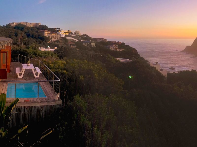 Stunning elevated view of the coastline and ocean, featuring a private timber deck with a swimming pool and modern balustrades.