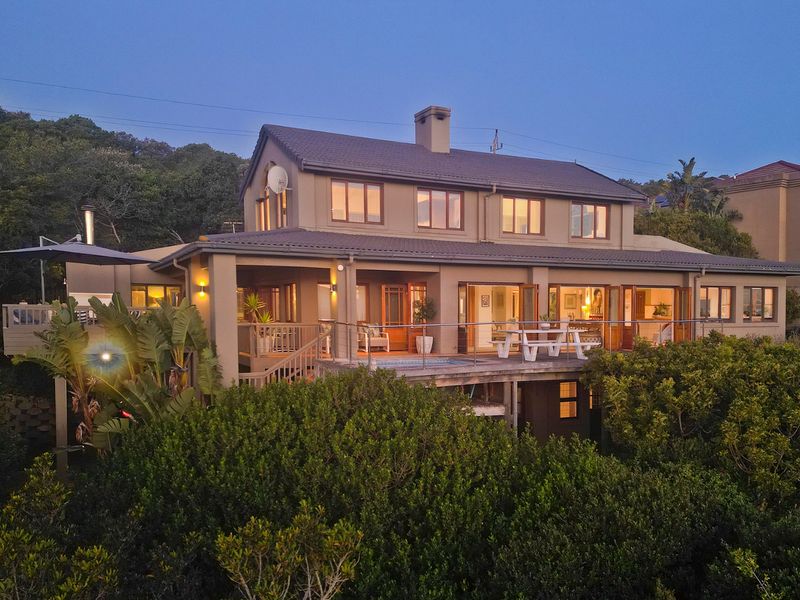 Rear elevation of a multi-story house featuring a spacious raised timber deck, integrated pool, and large sliding glass doors overlooking lush greenery.
